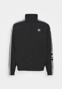 Svart zip-up jacka i lättvävt material, med vita tre-randiga detaljer på ärmarna och en liten vit logotyp på bröstet.