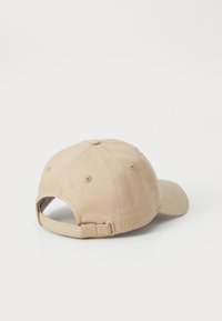 Beige bomuldske caps med en buet skygge, justerbar strop bagpå og syet detaljer. Glat tekstur med et enkelt design.