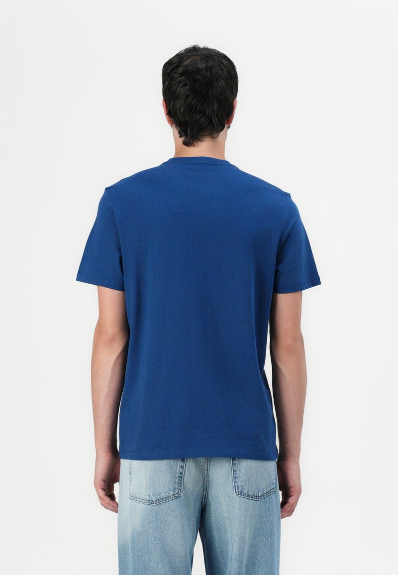 Niebieska bawełniana koszulka z okrągłym dekoltem, krótkimi rękawami i luźnym krojem. Prosty wzór, bez widocznych logo ani wzorów, widok z tyłu.