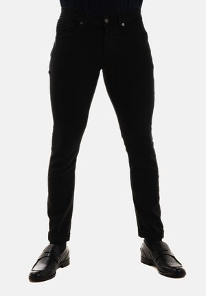 Jeans in denim nero con una vestibilità aderente, dotati di tasche frontali, chiusura con bottone e orli arrotolati. Abbinati a scarpe in pelle nere.