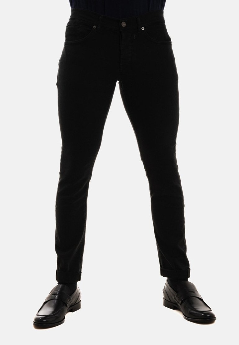 Jeans in denim nero con una vestibilità aderente, dotati di tasche frontali, chiusura con bottone e orli arrotolati. Abbinati a scarpe in pelle nere.