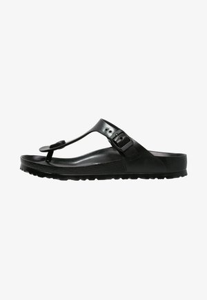 Sorte sandaler med T-rem design, lavet af glat læder med en tekstureret fodseng og en gribende gummisål. Justerbar spænde lukning.