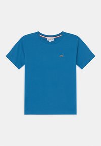 Sininen puuvillapaita lyhyillä hihoilla, pyöreällä kaula-aukolla ja pienellä vihreällä Lacoste-logolla vasemmalla puolella rintaa.