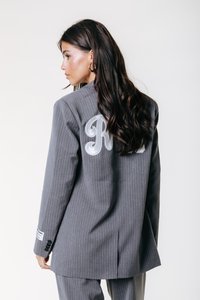 Grå stribede blazer med en skræddersyet pasform. Har et broderet "R" på ryggen, samt knapede manchetter med et label detajle på ærmet.