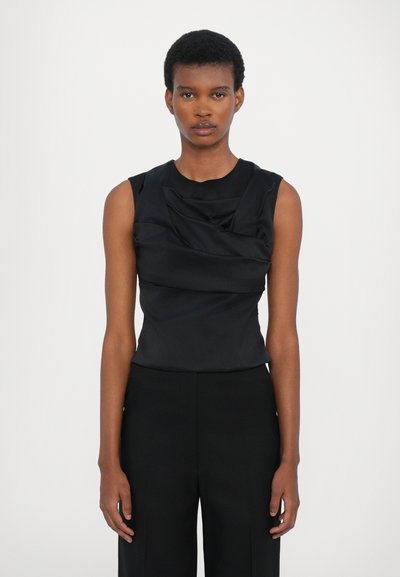 Top negro sin mangas con escote drapeado y tejido texturizado, combinado con pantalones negros de cintura alta, que presenta una silueta estilizada.