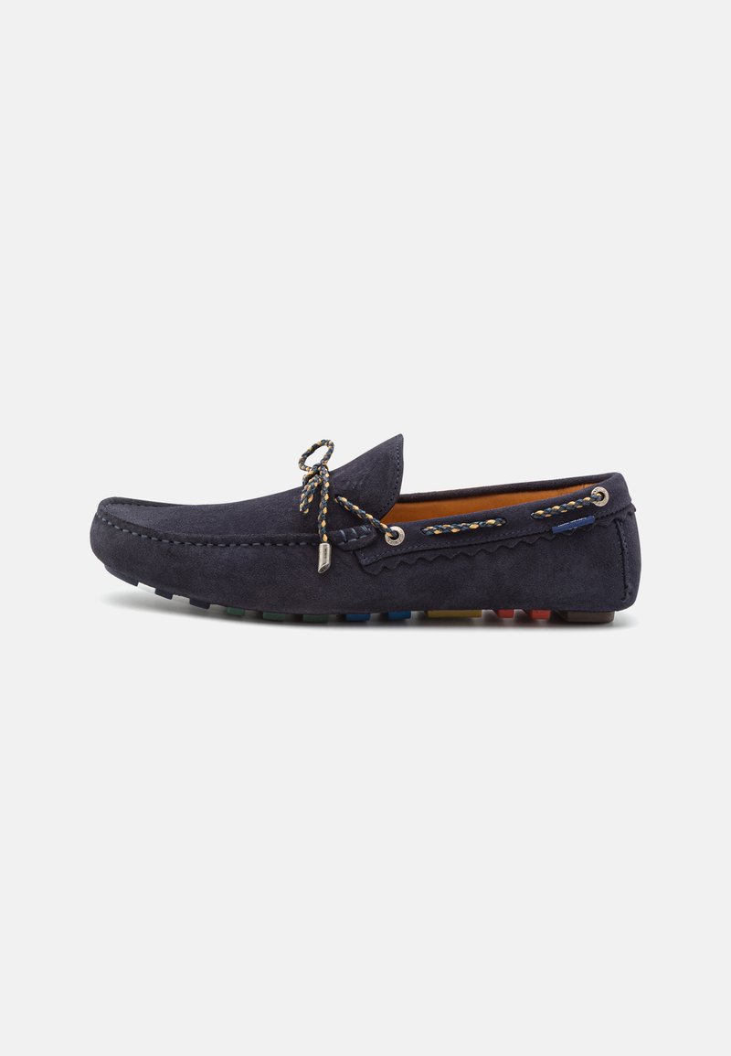 Pantof suede de tip mocasin în nuanță de albastru marin, cu o margine cusută, nod decorativ și talpă din cauciuc multicoloră pentru o aderență sporită.