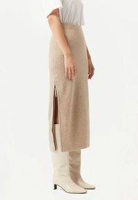 Beige, ribbad stickad kjol med en åtsittande midja och sidoflikar, kombinerad med knähöga beige stövlar med klack.