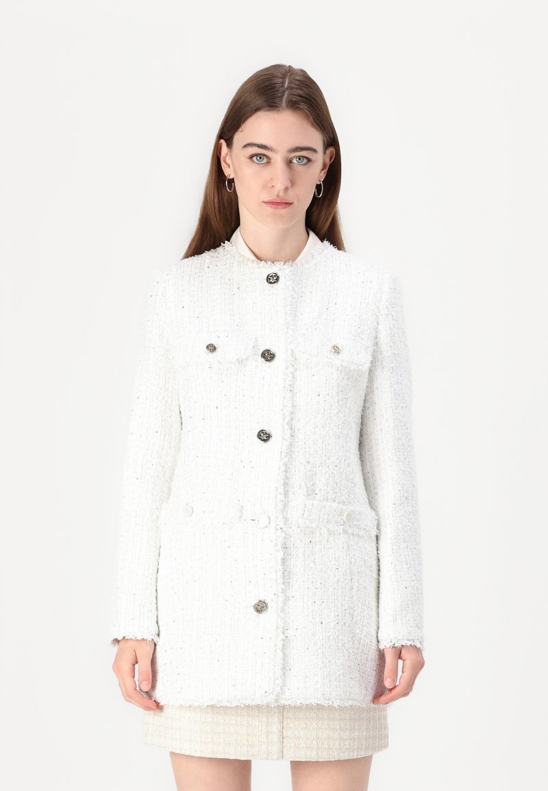 White tweed jacket with metallic buttons, textured fabric, two front pockets, and a high neckline. Features a straight cut and long sleeves.