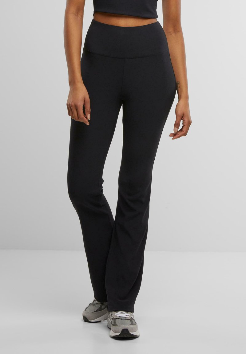 Schwarze, dehnbare Yogahosen mit hohem Bund und ausgestelltem Bein. Glatte Textur, keine sichtbaren Muster oder Verzierungen.