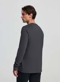 Szara koszulka z długim rękawem wykonana z miękkiej bawełny, z okrągłym dekoltem i dopasowanymi rękawami. Prosty design bez wzorów i ozdób.