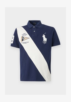 Granatowa koszulka polo z białym ukośnym paskiem, haftowanym logo gracza polo, naszywką klubu jachtowego oraz numerem 3 na prawej rękawie.