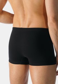 Boxer neri realizzati in tessuto morbido, con un design aderente, una fascia in vita liscia e senza loghi o motivi visibili.
