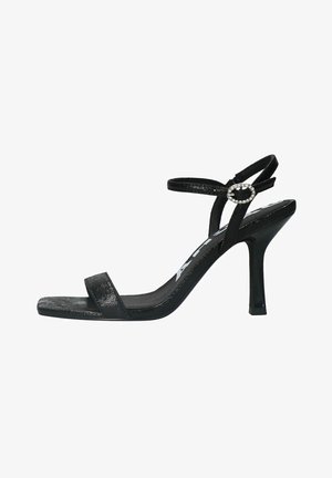 Sandales à talons hauts noires avec une finition brillante, présentant un design de lanière simple et un accent décoratif de strass sur la lanière de cheville.