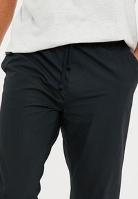 Marineblauwe joggingsbroek van lichtgewicht stof, met een elastische tailleband en een zachte textuur. Minimalistisch ontwerp zonder zichtbare patronen.