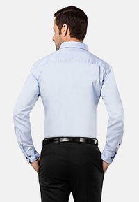 Lichtblauw overhemd met lange mouwen, knoopmanchetten en een klassieke kraag, gecombineerd met zwarte broek en een zwarte riem.