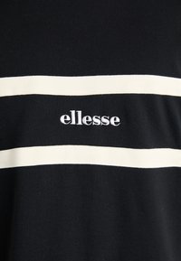 Juodas marškinėliai su horizontaliais baltais dryžiais ir išsiuvinėtu prekės ženklu "ellesse" centre. Pagaminti iš medvilnės, turi lygaus paviršiaus tekstūrą.