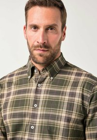 Geruit overhemd met knopen in groen, beige en paars. Beschikt over een kraag, een voorzak en lichte knoopaccenten op een textuurstof.