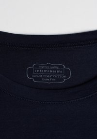 Tmavě námořnický tričko s límcem a štítkem s nápisem "intimissimi 100% SUPIMA® COTTON Extra Fine." Hladká textura, rovnoměrné švy.