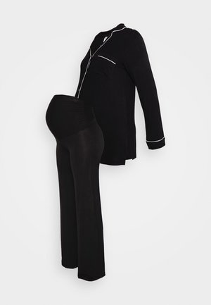 Zwart zwangerschapspyjamaset met een lange mouwen top met een zak en witte piping, gecombineerd met aansluitende zwarte broeken ontworpen voor comfort.