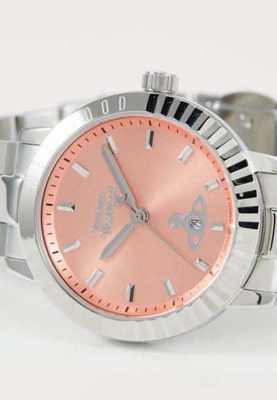 Ασημί ρολόι από ανοξείδωτο ατσάλι με ροζ χρυσό καντράν, που διαθέτει ασημί δείκτες και δείκτες ωρών, καθώς και κορώνα στο πλάι.