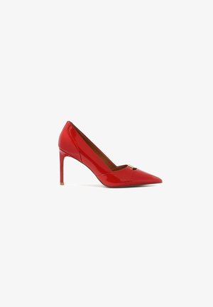 Escarpin en cuir verni rouge avec un bout pointu et une petite découpe en cuir. Présente un accent doré à l'avant.