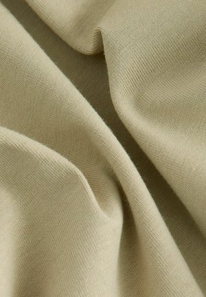 Tissu beige avec une texture lisse, présentant un tricot doux et léger. Le matériau présente de subtiles variations de couleur et de motifs de tissage.