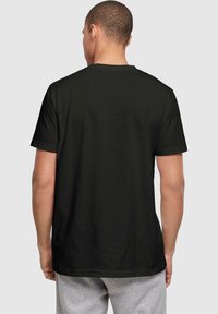 Camiseta negra de manga corta hecha de algodón, con cuello redondo y un corte relajado, con la espalda lisa y sin patrones ni acentos visibles.