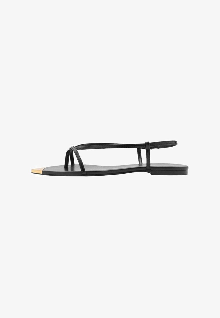 Mustat litteät sandaalit minimalistisella designilla, joissa on ohuet hihnat ja kultakoristeinen varvaskuppi. Tasainen pinta pohjassa.