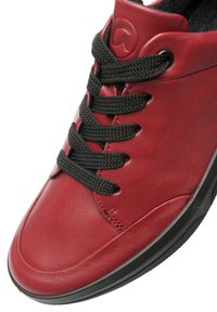 Rote Leder-Sneaker mit schwarzen strukturierten Schnürsenkeln, runder Zehenpartie und schwarzer Gummisohle. Auffälliges Logo auf der Zunge eingeprägt.