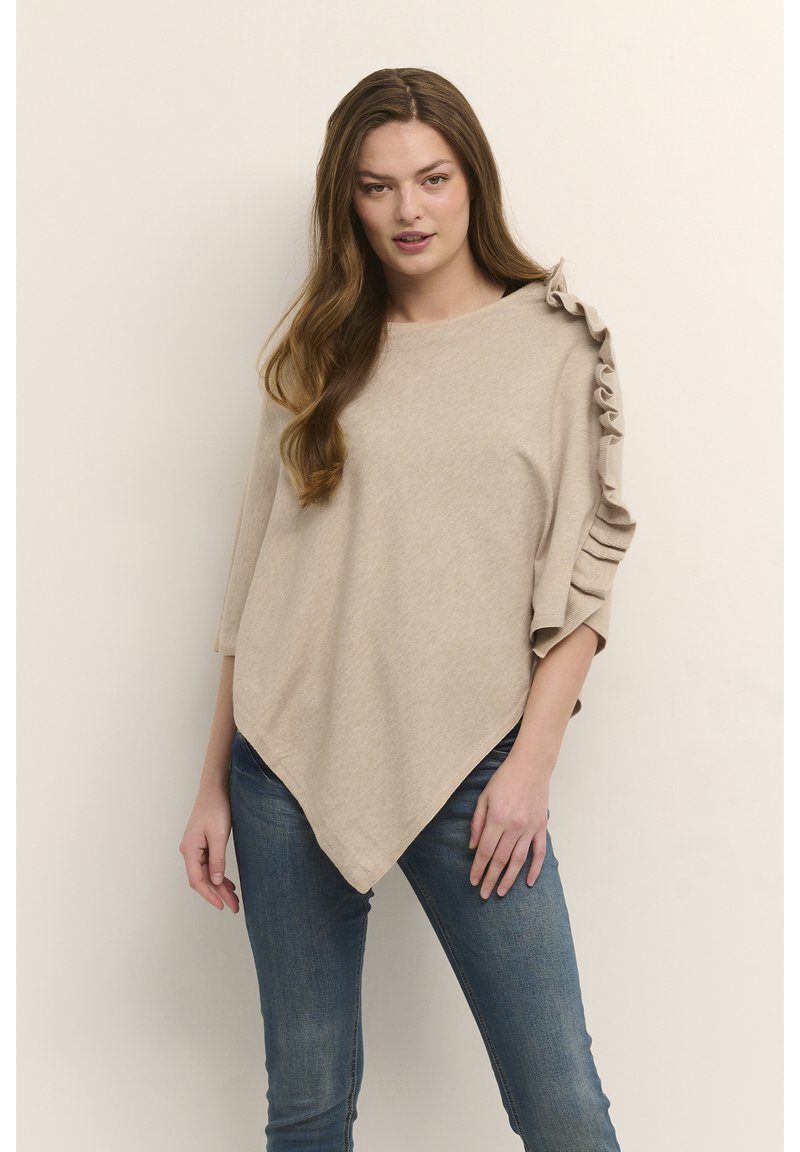 Smėlio spalvos viršus su laisvu kirpimu, asimetriniu kraštu ir tekstūriniu raukinių dekoravimu ant peties. Derinama su melsvais siauro kirpimo džinsais.