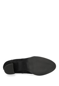 Zapato de ante negro con punta redondeada y tacón bajo y grueso. Suela de textura suave con surcos horizontales. Marca sutil en la plantilla.