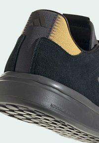 Czarne zamszowe i szare syntetyczne buty, z żółtym tekstylnym akcentem, teksturowaną podeszwą oraz detalem logo na pięcie.