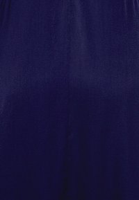 Tecido azul marinho com uma textura lisa, apresentando um detalhamento mínimo e um design simples. O material parece leve e suave.