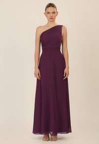 Ein trägerloses bodenlanges Kleid aus tiefpurpurnem Chiffon mit gerafftem Oberteil und glattem Rock. Silbernfarbene Riemchenabsätze vervollständigen den Look.