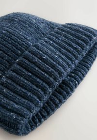 Knit hat in dark blue with ribbed texture and lighter speckled fibers. Features a rolled brim and soft, thick material.
