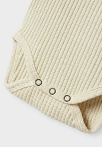 Ribbet, cremefarvet baby romper med en blød tekstur. Har tre metal snaplukninger forneden og rund halsudskæring.