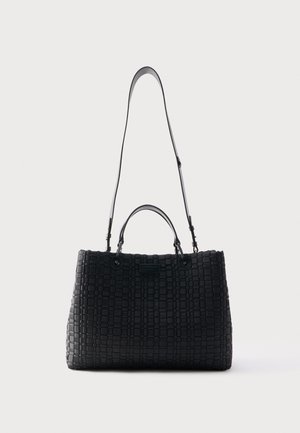 Černá pletená kožená kabelka se dvěma krátkými úchyty a jedním dlouhým nastavitelným ramenním popruhem, zobrazena na jednoduchém světlém pozadí.