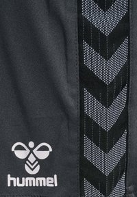 Zwarte stoffen shorts met een getextureerd zijpaneel met een chevronpatroon in het wit. Merkenlogo "hummel" in het wit aan de onderkant.