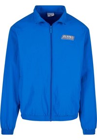 Blue windbreaker jacket with a full front zipper, elastic cuffs, and waistband. Features 'KANI SPORT' logo on the upper left chest area.