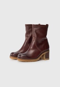 Bottines en cuir marron avec une surface lisse, un bout arrondi et un talon carré avec une base texturée et des accents cousus.
