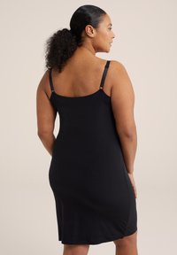 Fekete ujjatlan ruha egyenes szabással, vékony állítható pántokkal, sima textúrával és enyhe fodorral az alján.