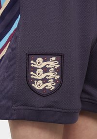 Pantaloni sportivi di colore viola scuro con una finitura testurizzata, dotati di un emblema cucito che mostra tre leoni e accenti di rosa rossa.