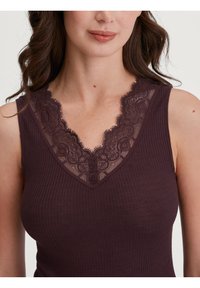 Bordeaux geribbeld tanktop met een V-hals, voorzien van ingewikkelde kantdetails langs de halslijn. Zacht materiaal met een nauwsluitende pasvorm.