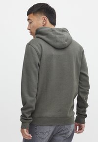 Oliven grønt hoodie med en blød tekstur, kengurulomme, og ribbede manchetter og kant. Hætten er fastsyet og designet til en afslappet pasform.