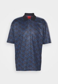 Polo bleu marine avec col noir, passepoil blanc aux manches et logos répétés "HUGO" et "GO" en motif bleu et bleu marine foncé.