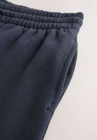 Mörkblå joggerbyxor i mjuk bomull med resårmidja och sidoficka, med en strukturerad, ribbad yta.