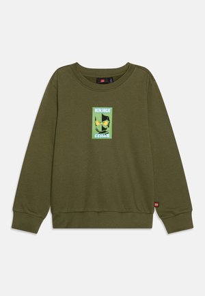 Sudadera verde hecha de un tejido suave. Presenta un gráfico cuadrado con la cara de un personaje y el texto "NINJAGO" en colores contrastantes. Puños acanalados.