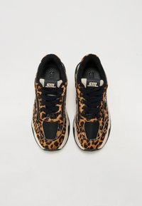 Sneakers med leopardmønster featuring svarte mesh-detaljer, teksturert semsket skinn, hvit mellomsåle og helt svarte snøringer. Tydelig merkevare på tunga.