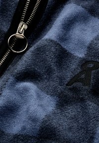 Fleecejacke mit blau-grauem Muster, silbernem Reißverschluss und gesticktem Logodetail. Weicher Stoff mit einem subtilen Glanz.