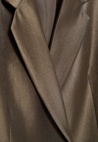 Brun satinblazer med en reverskrave med hak, der har en glat struktur og diskret glans. Veldefinerede revers viser et skræddersyet design.